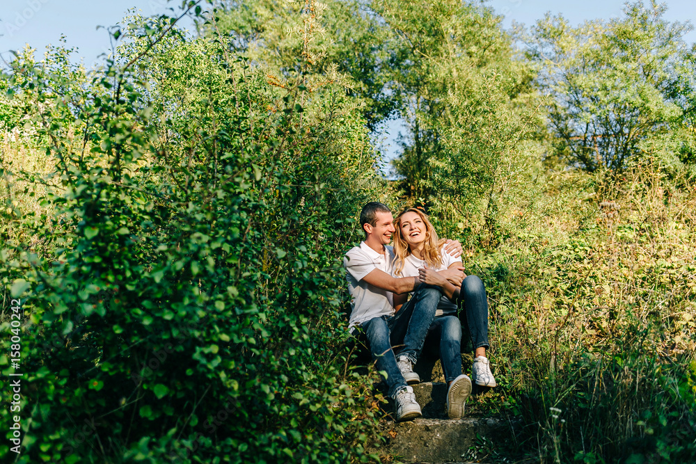 Happy boy and girl sitting on the steps. Hugging and laughing together in the open air Happy boy and girl sitting on the steps. Hugging and laughing together in the open air