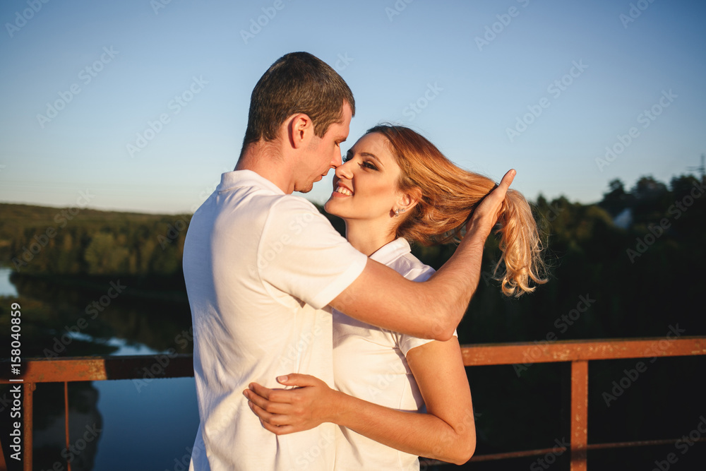 Two young lovers standing on the bridge and looking at each other with tenderness Two young lovers standing on the bridge and looking at each other with tenderness