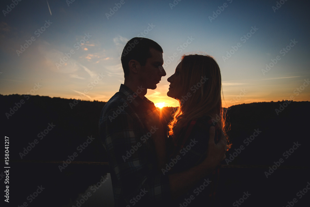 Romantic couple looking at each other against the sunset sky