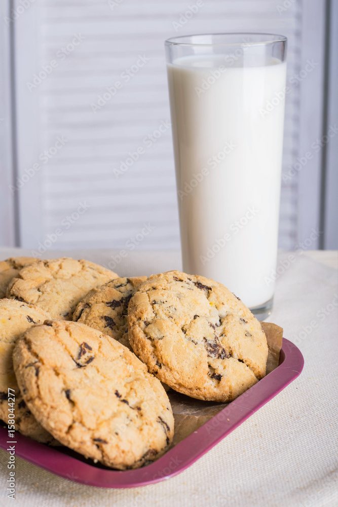 Chocolate biscuits and a glass of milk on a linen towel on a wooden table with a white background. Vintage view. Place for the inscription. Chocolate biscuits and a glass of milk on a linen towel on a wooden table with a white background. Vintage view. Place for the inscription.