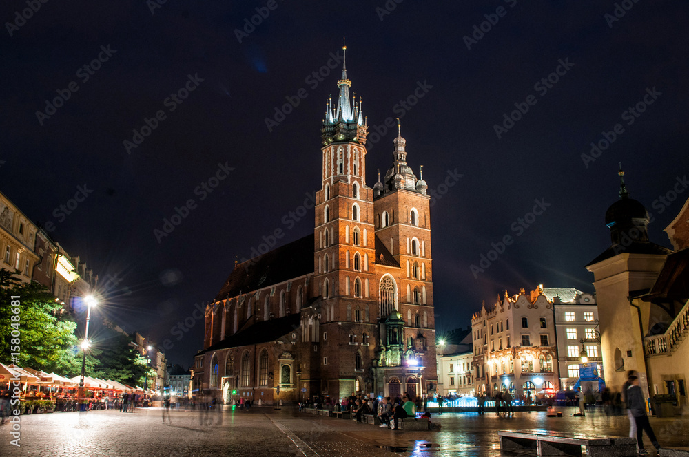 Evening illuminated Mary's Basilica with a square in the Polish city of Krakow