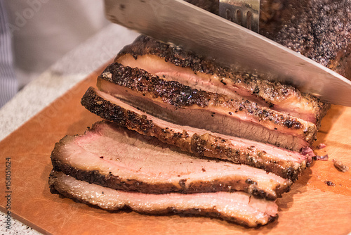 Barbecue beef brisket being cut on cutting board photo