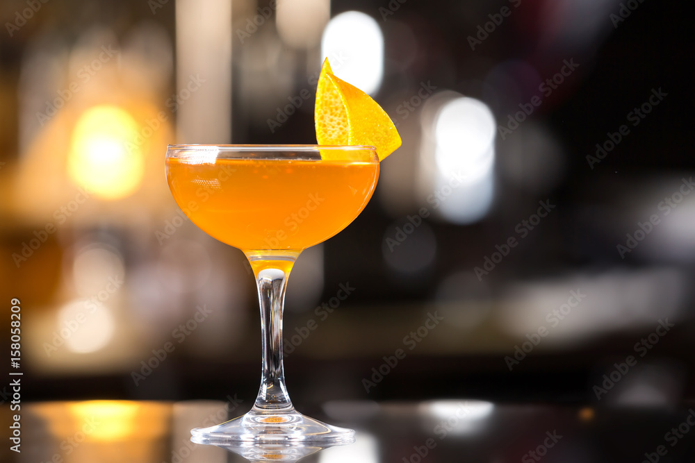 Glass of orange cocktail decorated with lemon at bar counter background. Glass of orange cocktail decorated with lemon at bar counter background.
