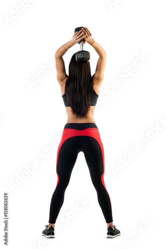 Sporty woman fitness model doing exercise with dumbbells, hands behind head in semi-bent position, rear view on white isolated background. Example exercises with dumbbells