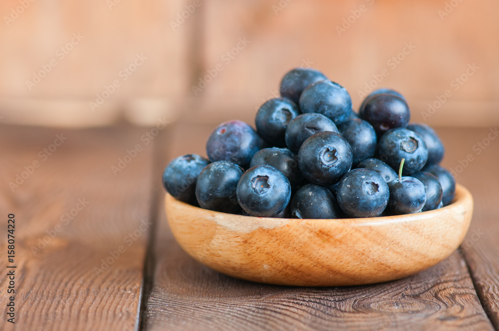 Close up of fresh raw blueberries served in a wooden plate. Wooden background and copy space. Helthy eating and gardening concept. Close up of fresh raw blueberries served in a wooden plate. Wooden background and copy space. Helthy eating and gardening concept.