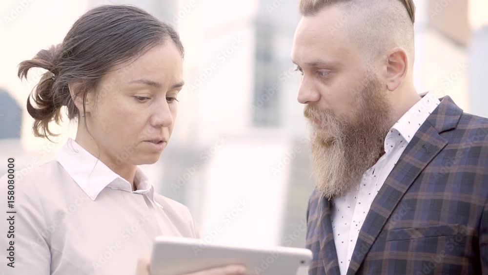 Young entrepreneurs of the banking market to discuss financial strategy standing on the street in the business center of the city. A bearded man in a stylish suit Young entrepreneurs of the banking market to discuss financial strategy standing on the street in the business center of the city. A bearded man in a stylish suit