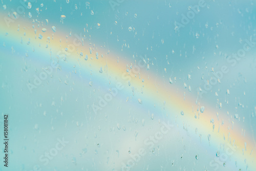 Water drops on a window with the rainbow in the background
