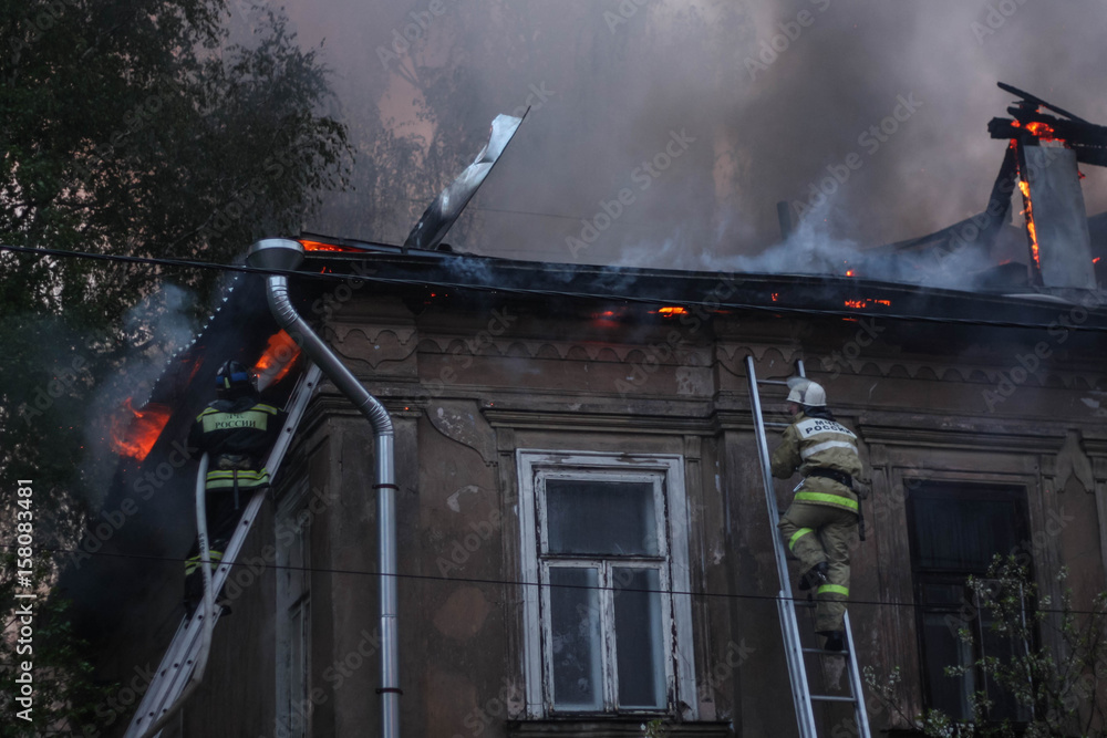 Fototapeta premium firefighters extinguish a fire in an old house