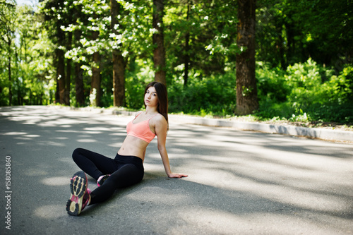 Fitness sport girl in sportswear sitting in road at park, outdoor sports, urban style.