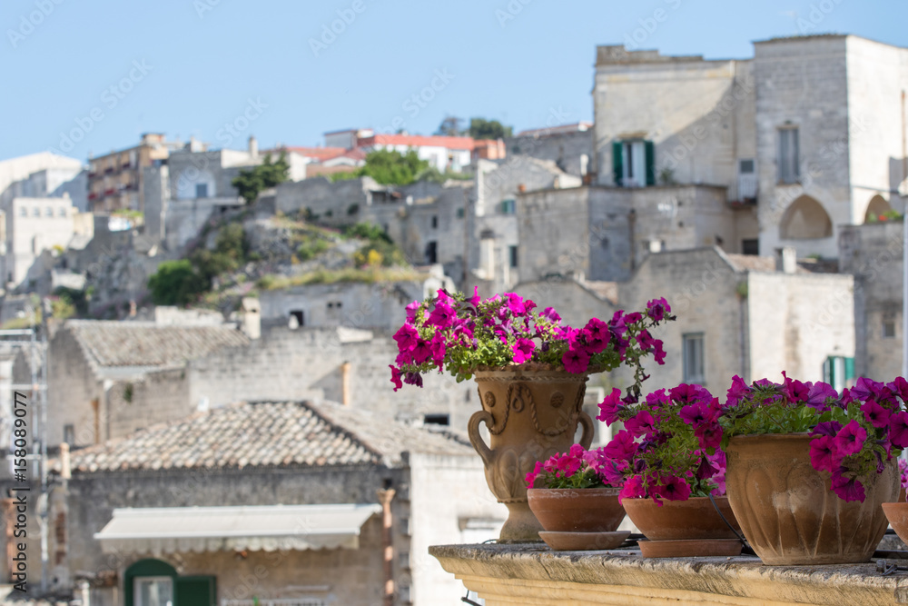 Naklejka premium Matera, Italy - May 20, 2017: Balcony of an ancient stone house of tufa with colorful fall colors