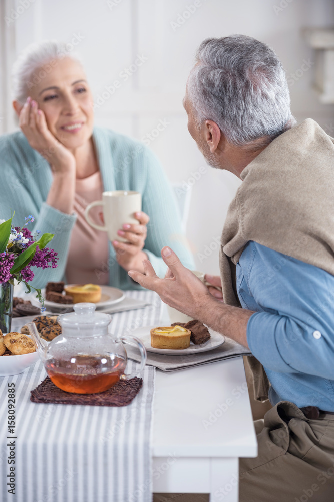 casual senior couple talking and having breakfast at home casual senior couple talking and having breakfast at home