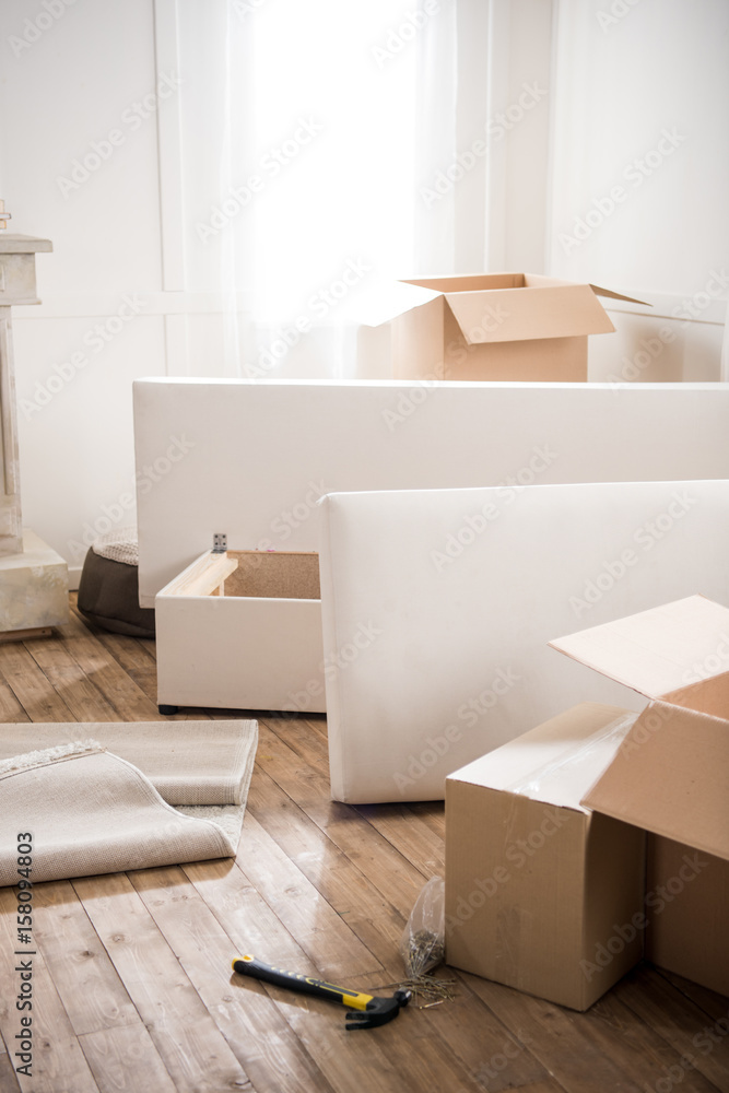Cardboard boxes, furniture and hammer with nails in empty room, relocation concept Cardboard boxes, furniture and hammer with nails in empty room, relocation concept