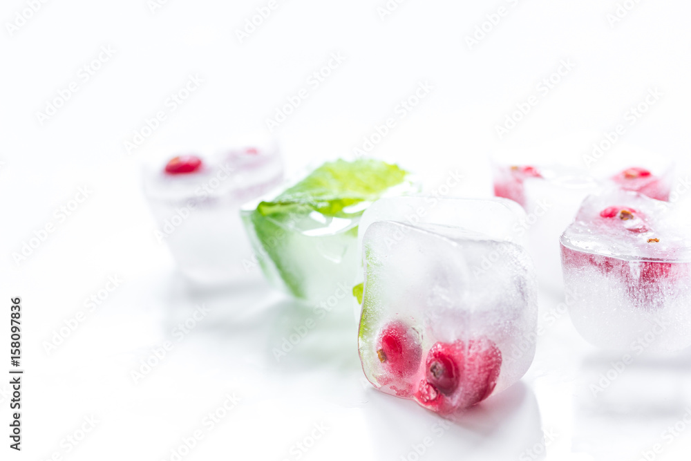 Ice cubes with berries and mint for summer drink on white background Ice cubes with berries and mint for summer drink on white background