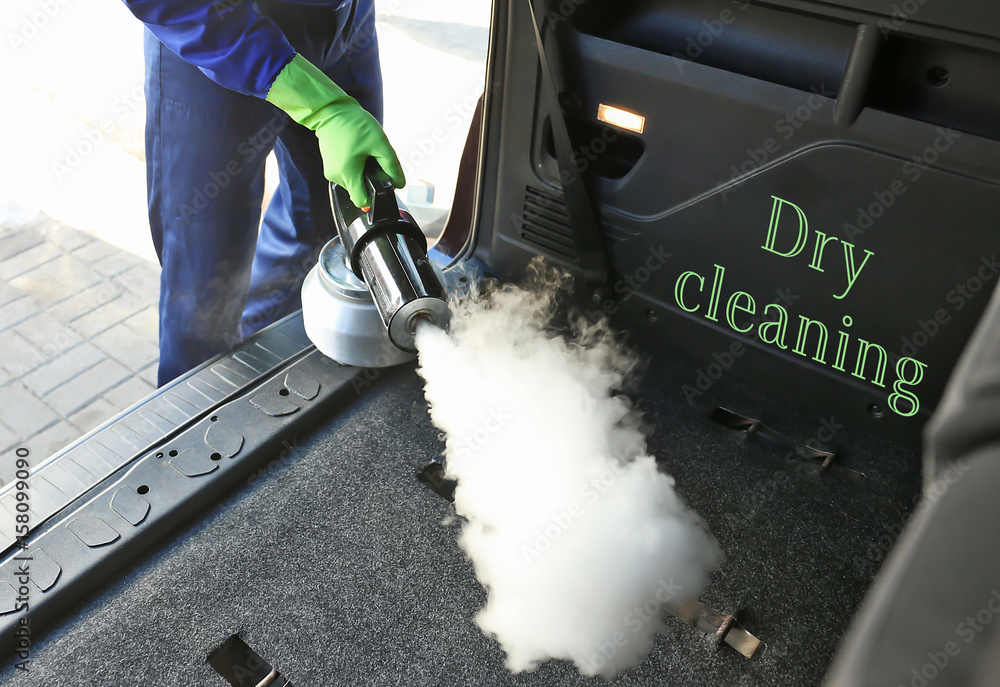 Handsome man cleaning car with hot steam