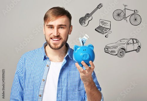 Happy young man holding pig...