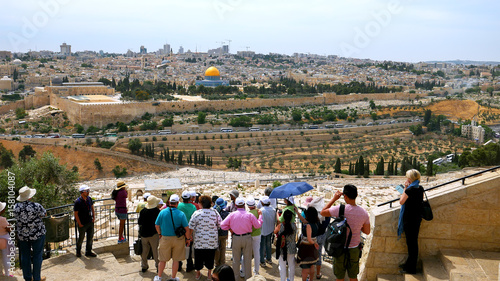 The guide shows the Jerusalem Old City view to the tourists. Mount of Olives is a famous and sacred Christian's place and it has a fantastic view to the Old Jerusalem.