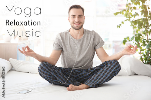 Man doing yoga and listenin...