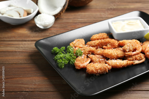 Plate with delicious coconut shrimps on table