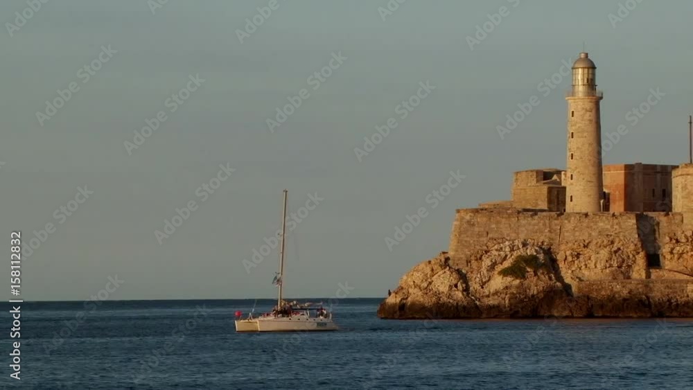 Catamaran sailing near ighthouse and Castle of los Tres Reyes del Morro in Havana, Cuba Catamaran sailing near ighthouse and Castle of los Tres Reyes del Morro in Havana, Cuba