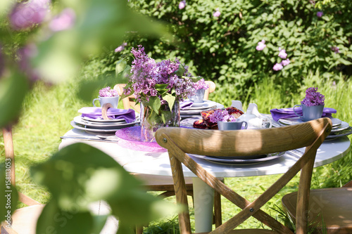 Beautiful table setting with lilac flowers decoration outdoors