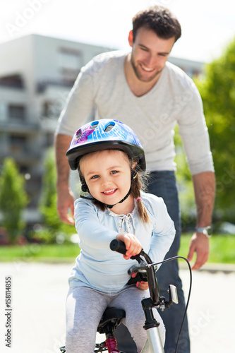 Girl learning to ride a bicycle with father 