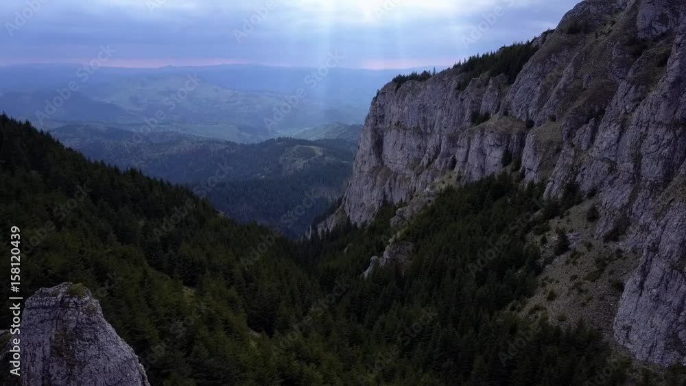 Aerial view flying in the mountains with sun rays in the distance Aerial view flying in the mountains with sun rays in the distance