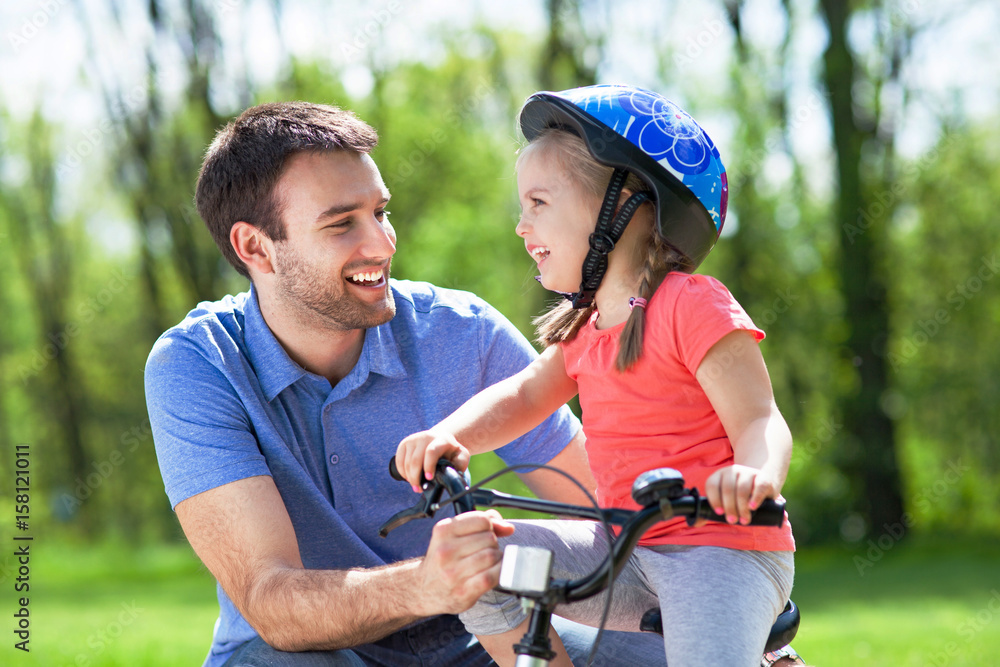 Girl learning to ride a bicycle with father
