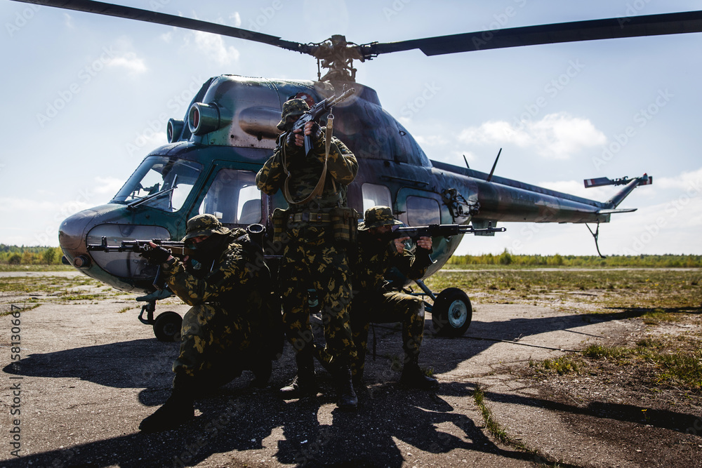 Photos of a group of military men with a gun in front of a helicopter Photos of a group of military men with a gun in front of a helicopter