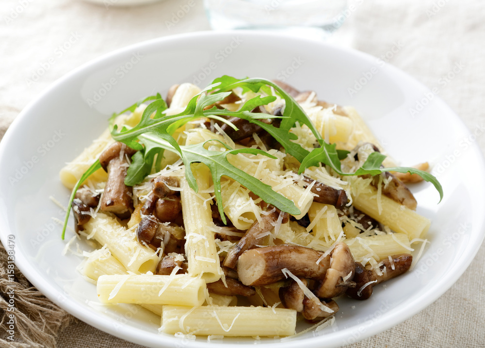 Pasta with mushrooms and arugula in white bowl Pasta with mushrooms and arugula in white bowl