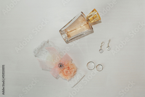 Perfume bottle and earrings lie on white table