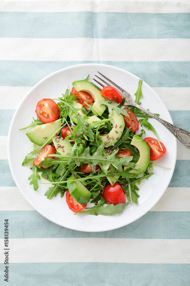 Green Avocado Salad with cherry tomatoes and arugula on a stripy background Green Avocado Salad with cherry tomatoes and arugula on a stripy background