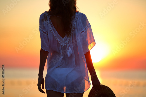 Woman on the beach at sunset. Summer vacations concept