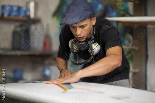 Surfboard shaper workshop, surf shop employee working on surfboard photo