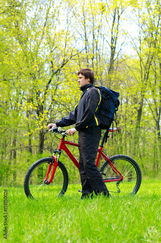 Man Cyclist with Bike and Backpack among the green nature