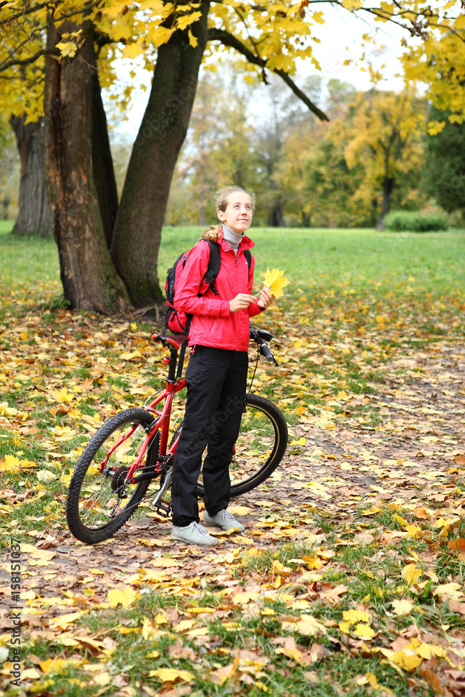 Fototapeta premium Young girl cyclist with bike enjoy vacation in autumn park