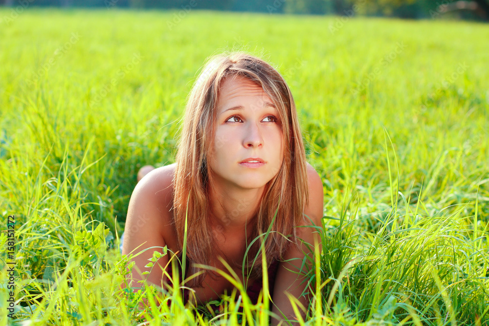 Portrait of young beautiful woman lying on green grass Portrait of young beautiful woman lying on green grass