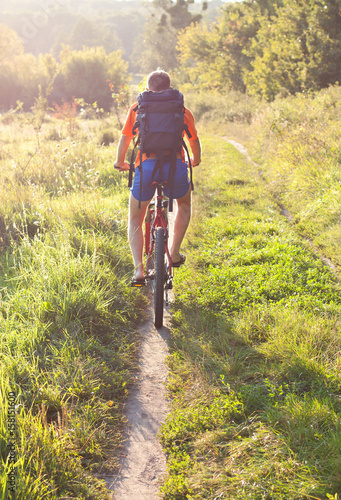 Cyclist riding away into the distance on the road. Back to us
