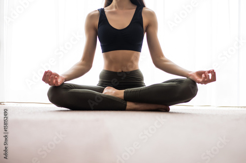Yoga meditation at home. Relax concept with unrecognizable spiritual young woman sitting. Caucasian concentrating model. Copyspace.