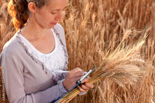 Woman agronomist writes results of his experiment in the wheat field