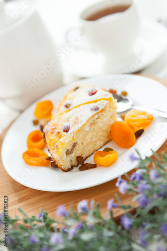 Cheese Pie with tea, dried apricot and raisins on a plate