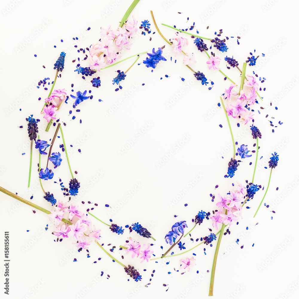 Round floral frame blue and pink flowers and petals on white background. Flat lay, top view.