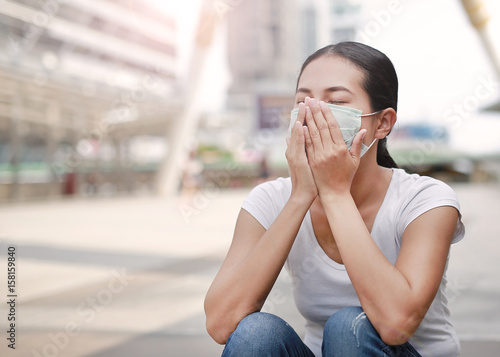 Woman wearing protective mask to protect pollution and the flu sitting at public area.