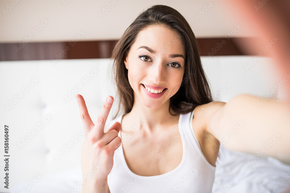 Beauty girl taking selfie from phone in the morning in bed at home Beauty girl taking selfie from phone in the morning in bed at home