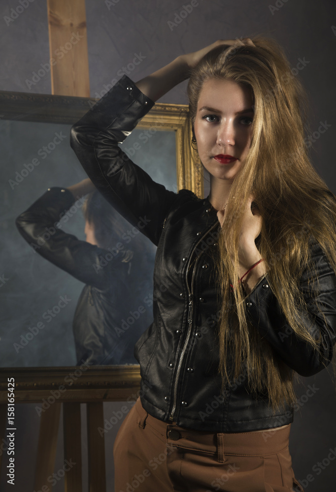 beautiful young woman in a leather jacket posing on a mirror background beautiful young woman in a leather jacket posing on a mirror background