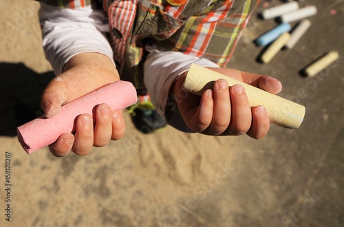 Children's hands and colorful chalk on a playground 