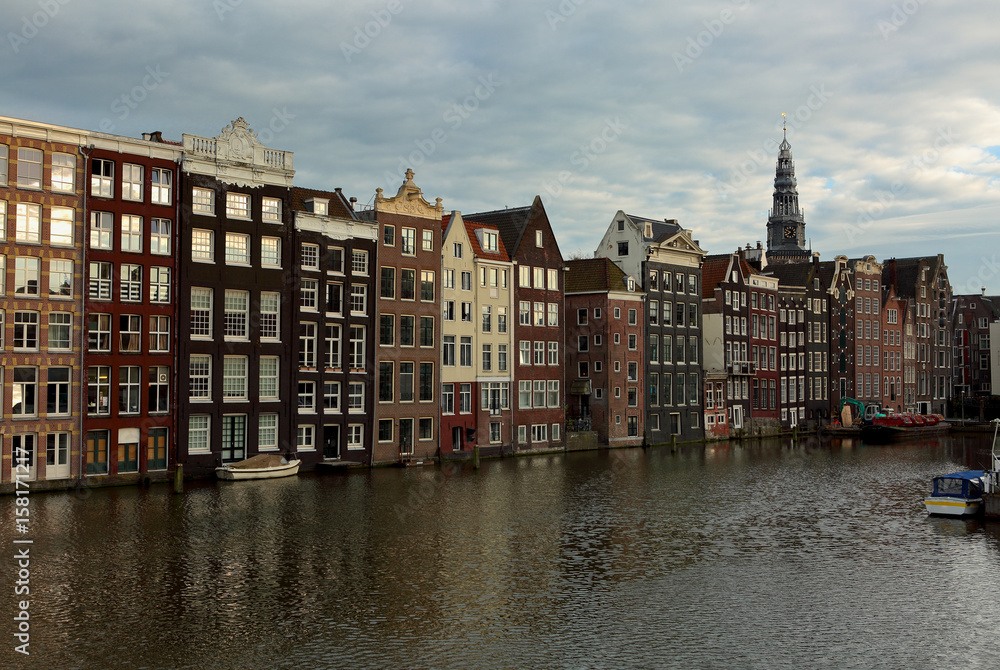 Beautiful panarama view of old Amsterdam buildings near the river under blue sky in dusk light