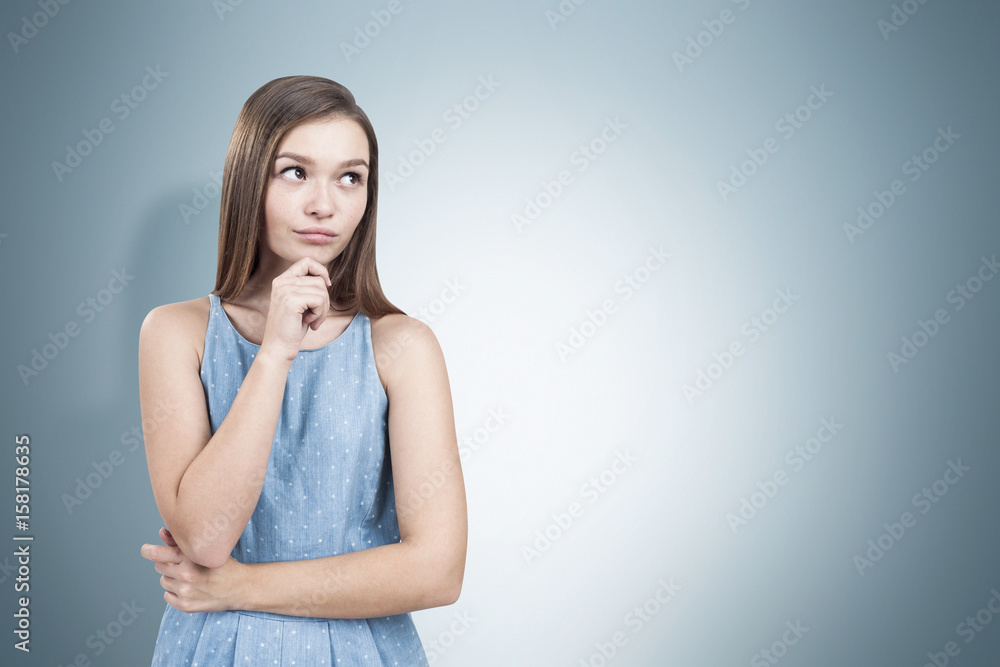 Pretty young woman in a blue dress thinking Pretty young woman in a blue dress thinking
