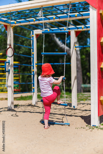 Adorable little girl enjoying her time in climbing adventure park on warm and sunny summer day. Summer activities for young kids. Child having fun on school vacations.