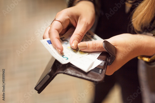 Close-up of a woman's hand holding wallet with banknotes and receipts photo
