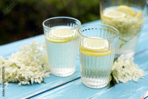 Two glasses of elderberry lemonade with fresh lemon and elderberry blossom